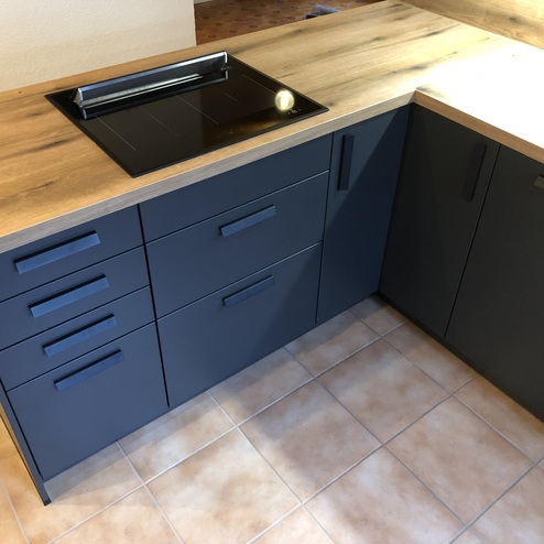Kückenzeile mit schwarzen Fronten und Holzarbeitsplatte