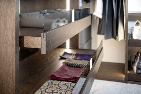 Schubladensystem in dunklem Holz Geöffnete Holzschublade mit Glaseinsatz in einer modernen Ankleide nach Maß