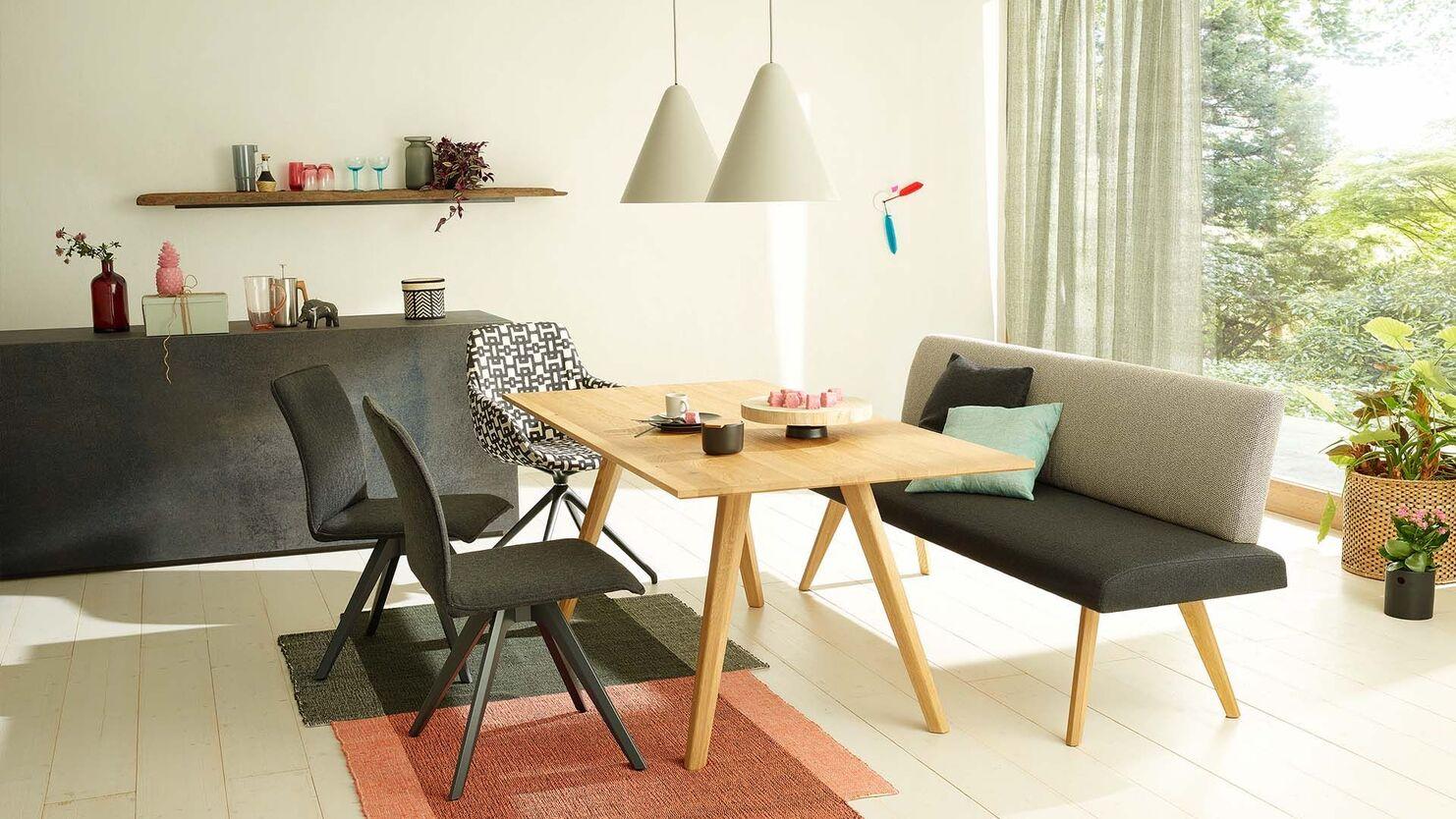 Essbereich mit Holzbank und Tisch Gemütlicher Essbereich mit Holzbank, Esstisch und modernen Stoffstühlen in hell eingerichteter Umgebung.