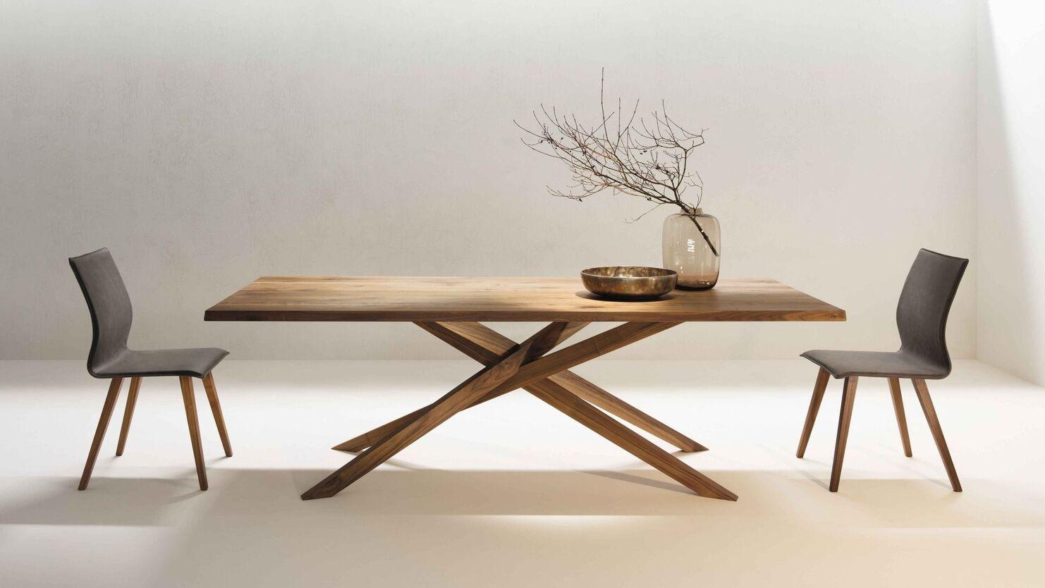 Design-Esstisch mit Holzgestell Minimalistisches Esszimmer mit Design-Esstisch aus Massivholz und zwei schlichten Stühlen vor hellem Hintergrund.