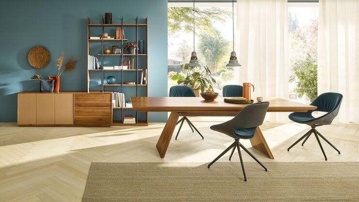 Modernes Esszimmer mit Holztisch Helles Esszimmer mit großem Holztisch, blauer Wandfarbe und Regalsystem, modern eingerichtet mit Tageslicht.