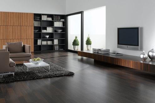 Wohnraumimpression mit verschieden dunklen Holzoberflächen für Einbauschrank, Sideboard und Bodenbelag